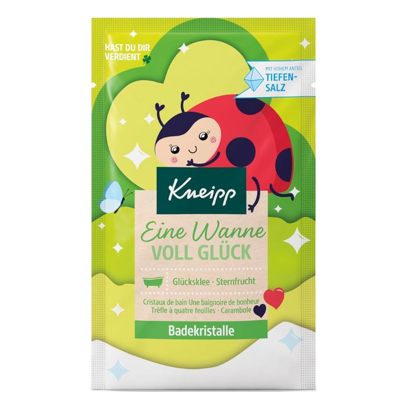 A package of Kneipp bath crystals in the 'Eine Wanne Voll Glück' flavor, featuring a bright green and yellow design with a cartoon ladybug on the front.