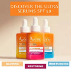 Three Avene ultra serum bottles with different colors on a beige background.