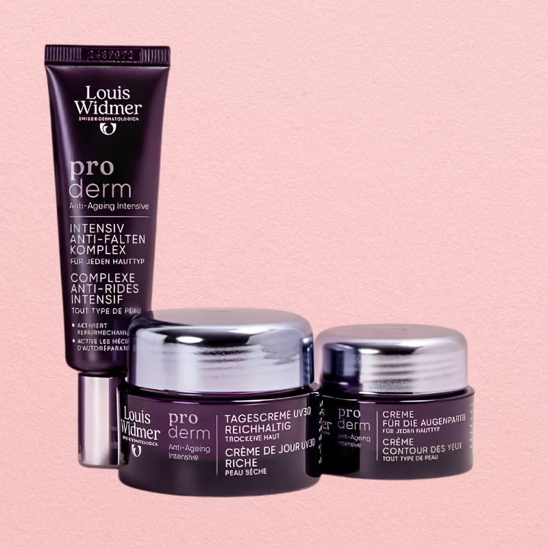 Louis Widmer pro derm skincare set featuring an intensive anti-aging tube and two cream jars with silver lids, arranged on a solid pale pink background.