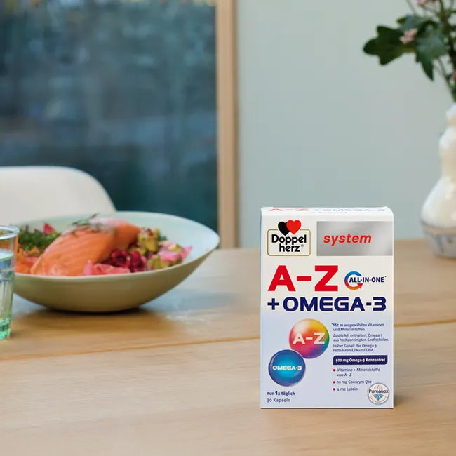 A package of Doppelherz A-Z Omega-3 capsules on the dining table with a plate of salmon and salad in the background